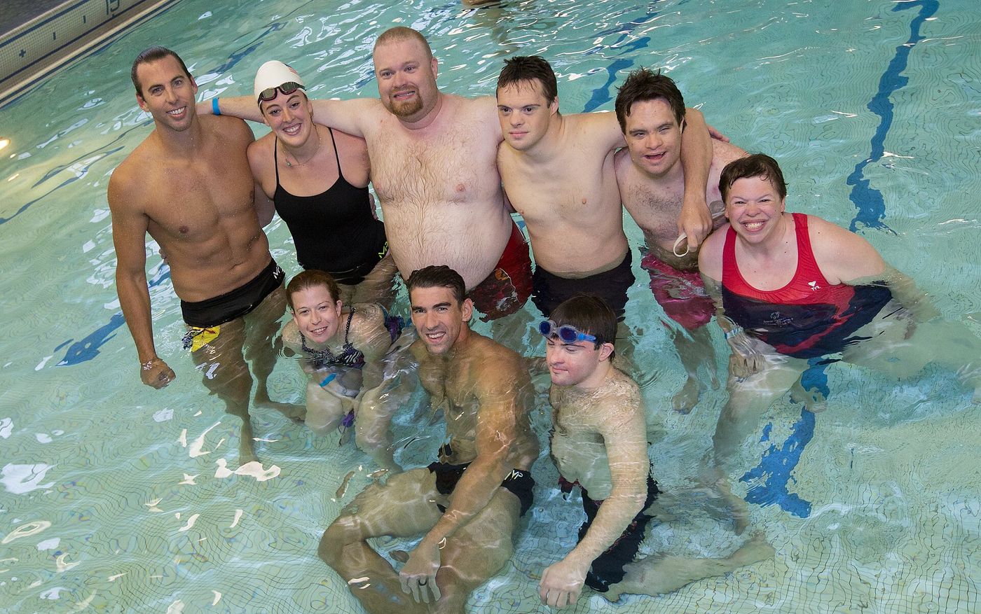Un groupe de nageurs souriants pose dans le bassin.